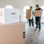 Two movers in uniform carrying boxes