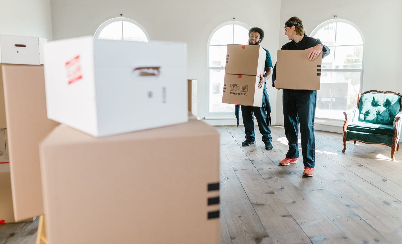 Two movers in uniform carrying boxes